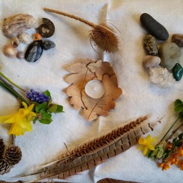 A table with a candle, flowers, shells and feathers