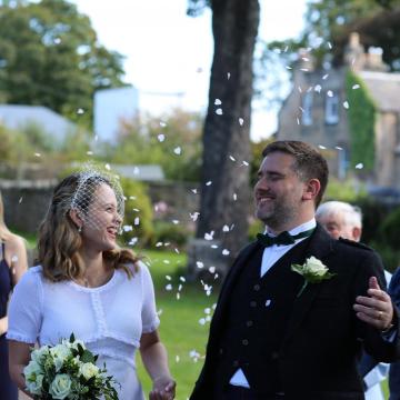 Couple in the garden being showered with confetti