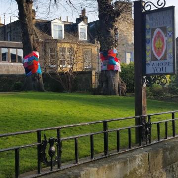 The church garden and welcome sign with two trees with giant scarves around their trunks